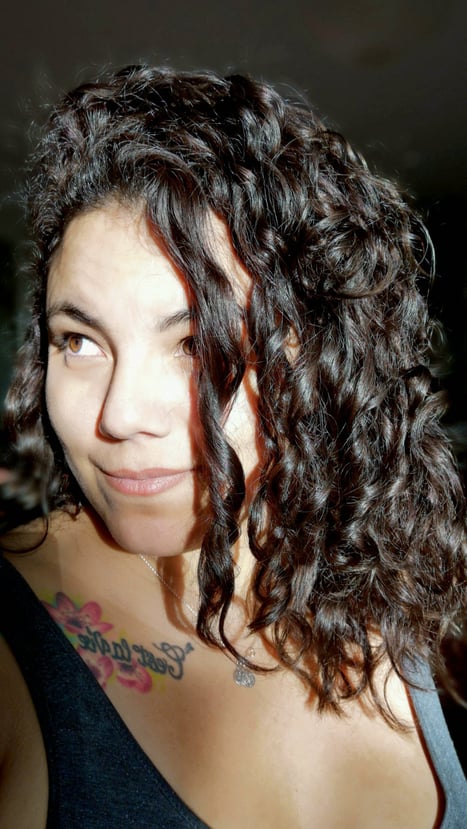 Retrato de Suzi Santana com olhar desperto e tatuagem de rosa, símbolo de consciência intuitiva