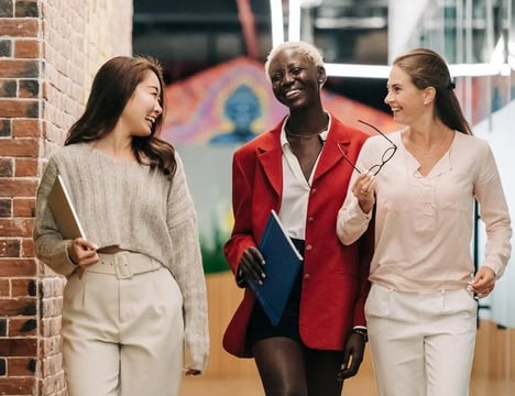 three women in business attire walking down a hallway