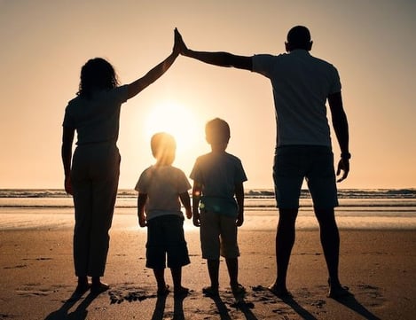 uma família de três pessoas em pé na praia