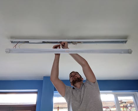 An electrician from Foxley Electrical installing a long light on a ceiling