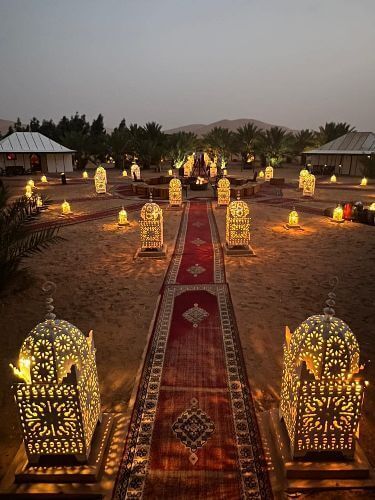 a long red carpet in desert with lamps around