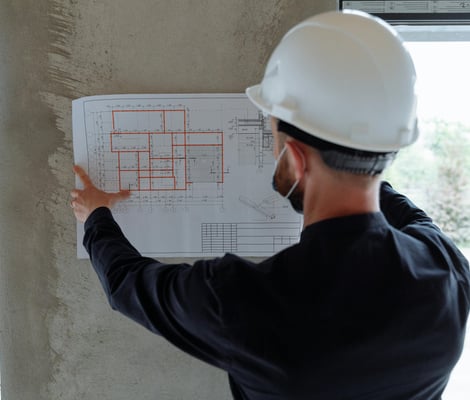 un operaio con il casco di protezione analizza un progetto