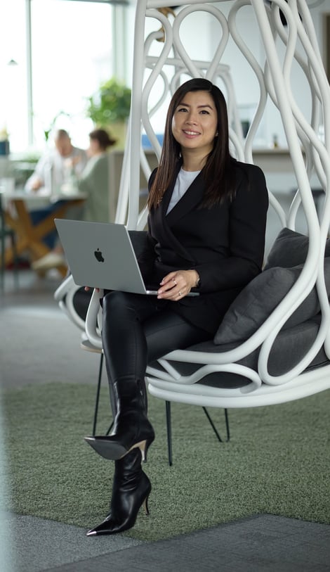Ka Ming Zwingenberger sitting in a hanging chair with a laptop on her lap.