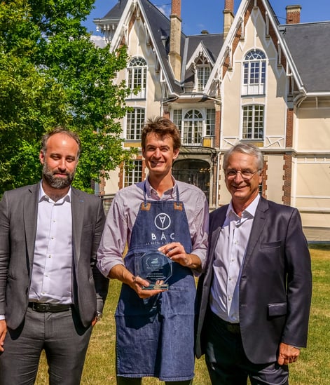Trois personnes qui posent devant un château avec un trophée en souriant