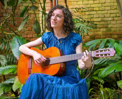 chanteuse guitariste en robe bleue chantant dans une serre