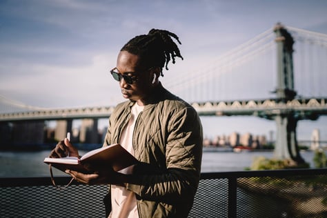 a man journaling outside while listening to music knowing it'll relieve his mental health swiftly