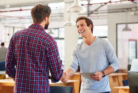 A man shaking hands with another man while smiling