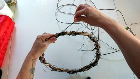 hands-wrapping-honeysuckle-vine-into-a-christmas-wreath-base