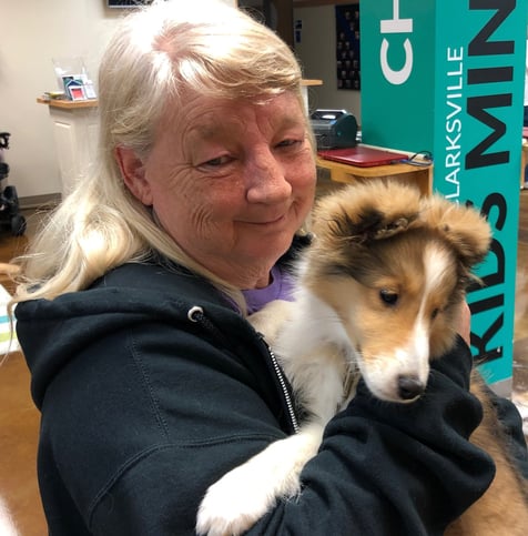 Tender Paws member Beth, holding puppy in her arms.