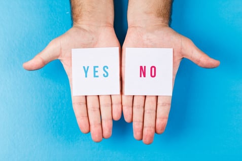 two hands holding up a card with the words yes no