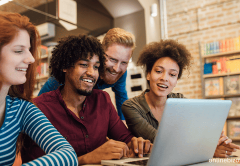 a group of people sitting around a laptop computer