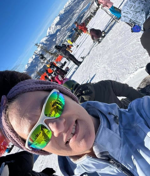 a woman in sunglasses and a hat skiing on a sunny day