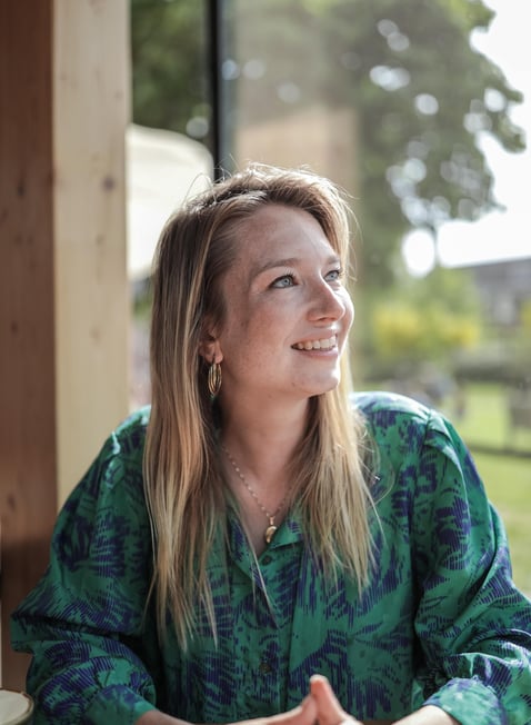 Een vrouw zit aan een tafel met een kop koffie.