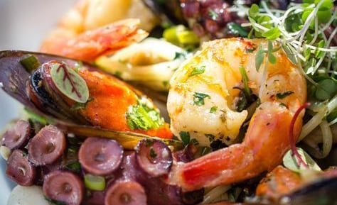 um prato de comida com camarão, camarão e legumes