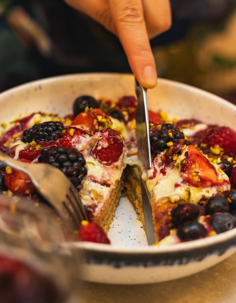 a person cutting into slices of fruit on a plate