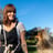 a woman in overalls and overalls sitting on a bench with a dog
