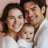 a man and woman holding a baby in a white shirt