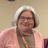 Woman with gray hair and glasses smiling.