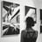A person stands in an art gallery observing framed photographs mounted on the walls.
