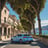 a blue car driving down a street with trees and buildings