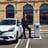 a man in a suit and tie tie standing in front of a car