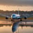 A commercial airplane with a light-colored fuselage is flying in a clear sky. The plane features distinct branding on the tail, which showcases a floral design. The aircraft's landing gear is deployed, suggesting it is about to land or is taking off.