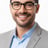a smiling man in a suit and glasses