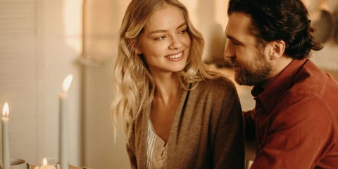 a man and woman sitting at a table with candles