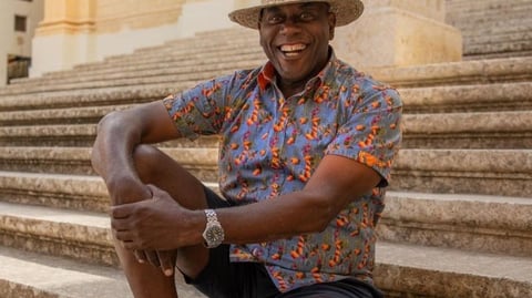 A man in a hat sits on some limestone steps.