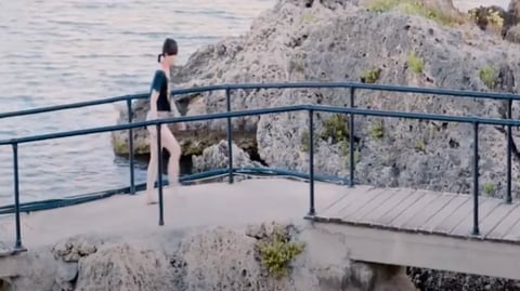 a woman walking across a pontoon.