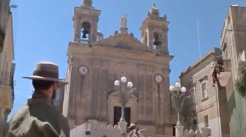 A man in a hat painting a church.