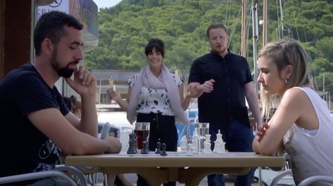 a man and woman sitting at a table with chess pieces.