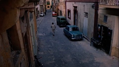 A man walking through a narrow street.