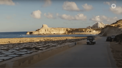 A car drives by the coast.