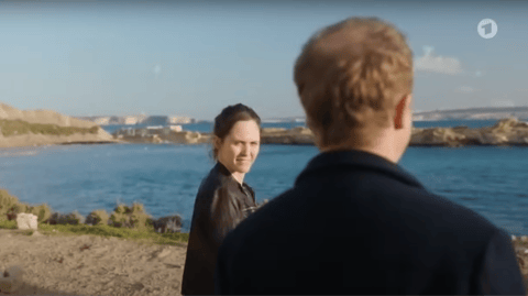 A man and woman stand looking at the sea.