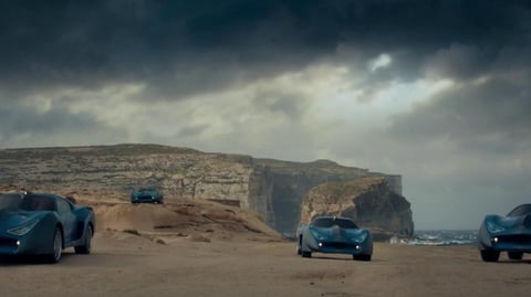 A group of cars parked on a rock beach.