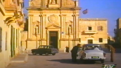 Cars parked in front of a church.