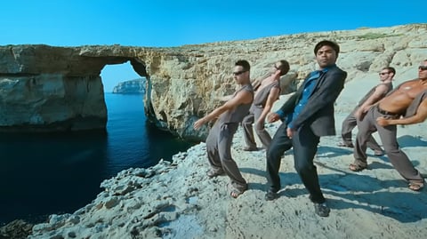 A group of men dancing on a cliff overlooking the Azure Window.