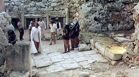 A group of people standing around a stone temple.