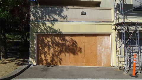 Garage opening boarded up with plywood. 