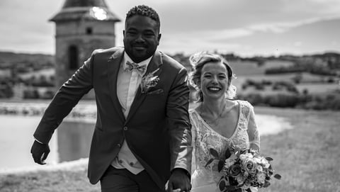 a bride and groom running on grass