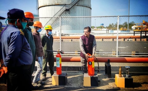 a man gives training of fire safety to a group of people  who wear suits and helmet 