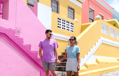 a man and woman holding hands and walking down a cobblestone street