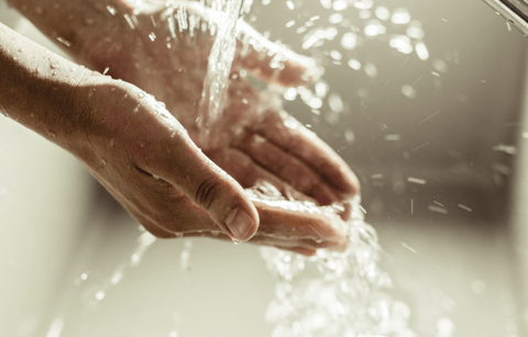 a person's hands are shown with water flowing from the water