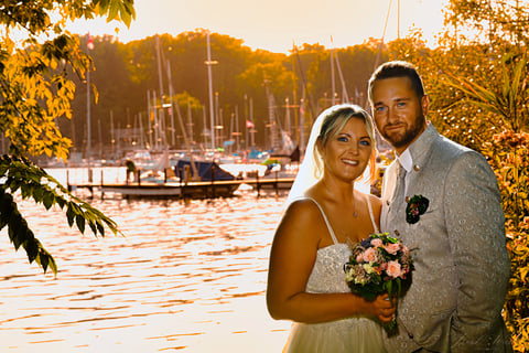 a bride and groom standing in front of a lake