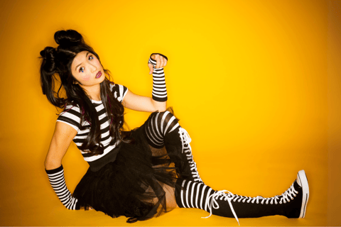 a Japanese woman in striped tights in front of orange background