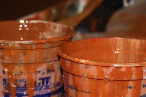 two buckets with paint and a paintbrush in the background