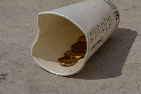 a empty cup on a street with a few coins inside