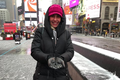 autora do blog, usando casaco comprido preto, e gorro pink em unma avenida com neve
