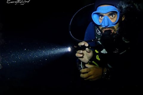 Advanced Scuba diver diving with a torch during a night dive at Gili Trawangan